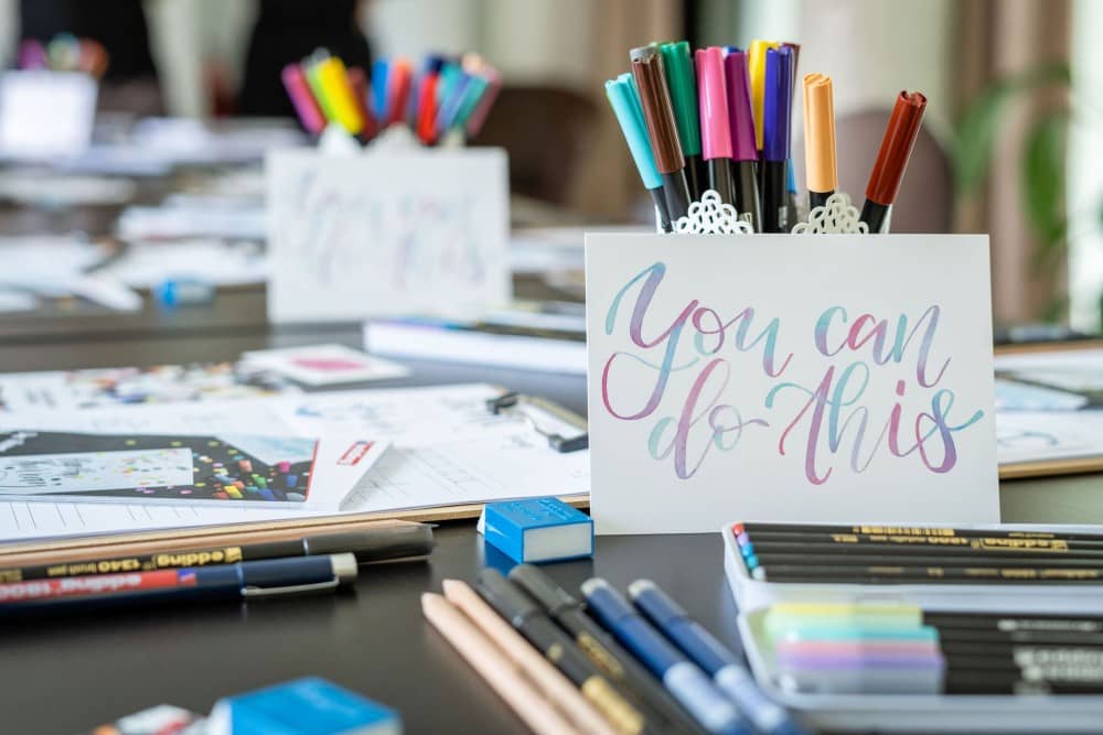 Handlettering-Utensilien sind auf einem Tisch verteilt