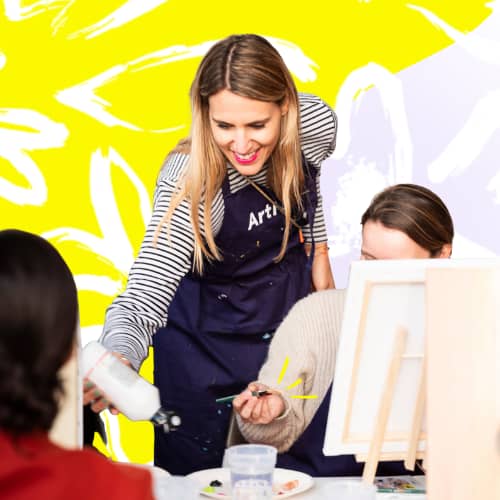 About us Aimie, Gründerin und CEO von ArtNight, schüttet bei einer ArtNight-Veranstaltung mehr Farbe für einen Teilnehmer aus.