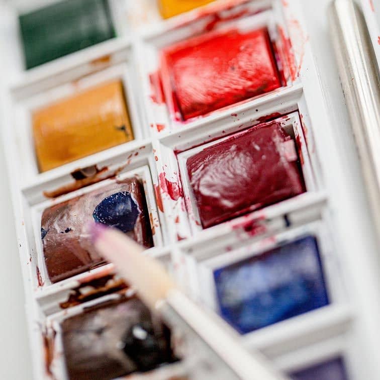Ein Pinsel nimmt eine Aquarellfarbe auf