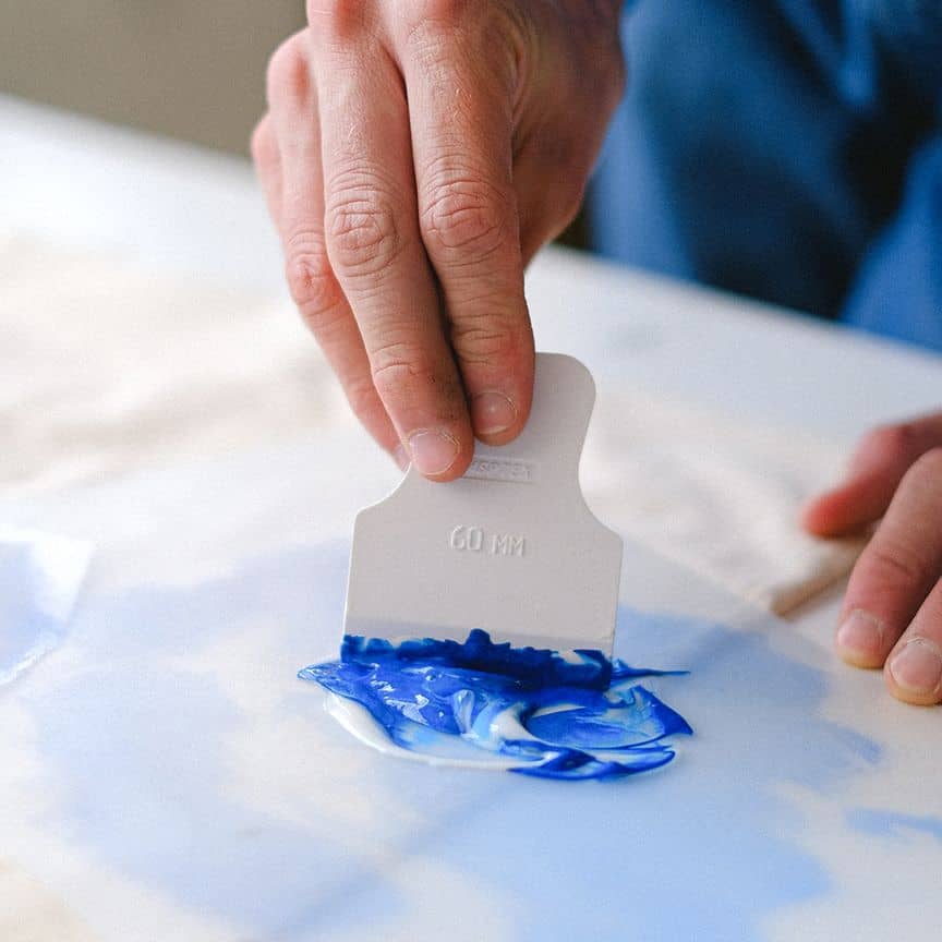 Blaue und weiße Farbe wird mit Malspachtel vermischt