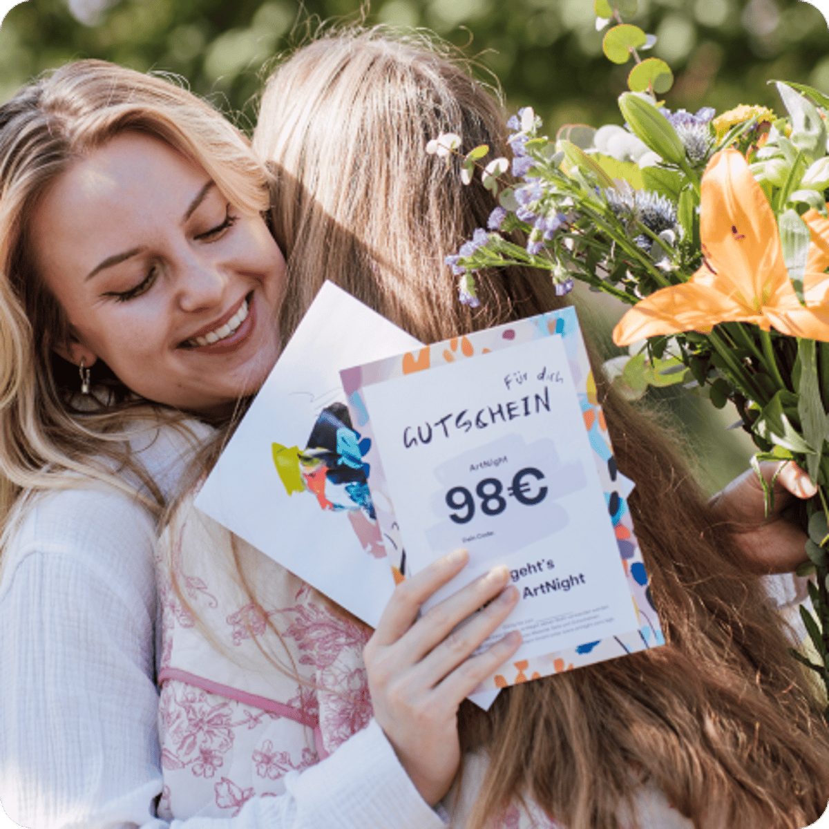 zwei Frauen, die sich umarmen und ein Blumengeschenk und eine ArtNight-Geschenkkarte teilen