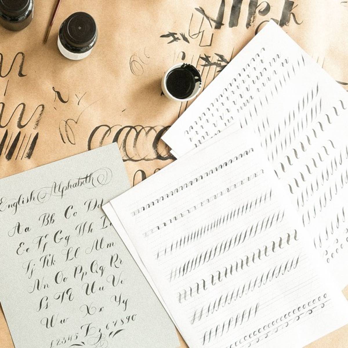 Blätter Papier mit Kalligraphie-Alphabeten Blätter Papier mit Kalligraphie-Alphabeten