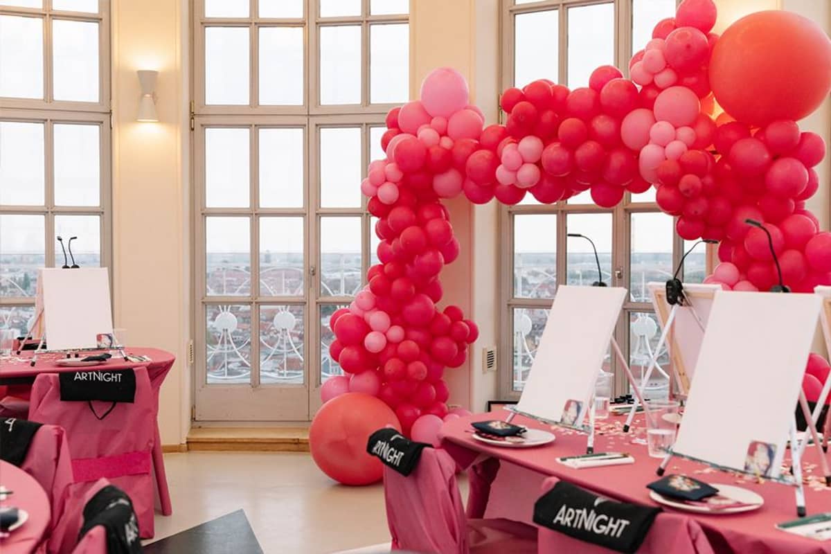 Tische mit Leinwänden und dahinter rote Ballons