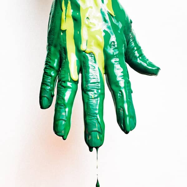 Hand mit tropfender grüner Farbe Hand mit tropfender grüner Farbe