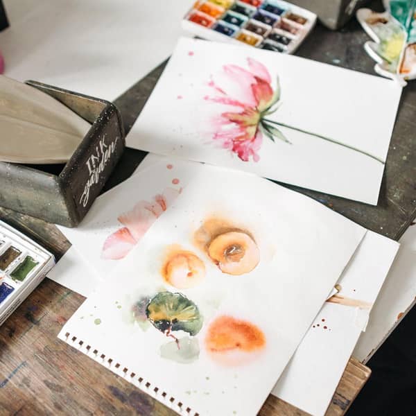 Aquarellbilder auf einem unordentlichen Tisch verteilt Aquarellbilder auf einem unordentlichen Tisch verteilt