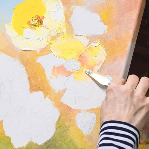 Es werden mit einem Spachtel Blumen auf einer Leinwand eingearbeitet