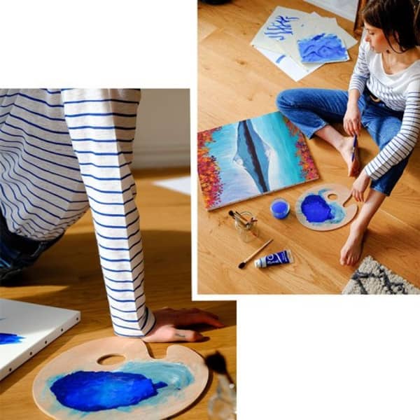 Eine Frau malt zur Entspannung auf dem Boden ein Bild