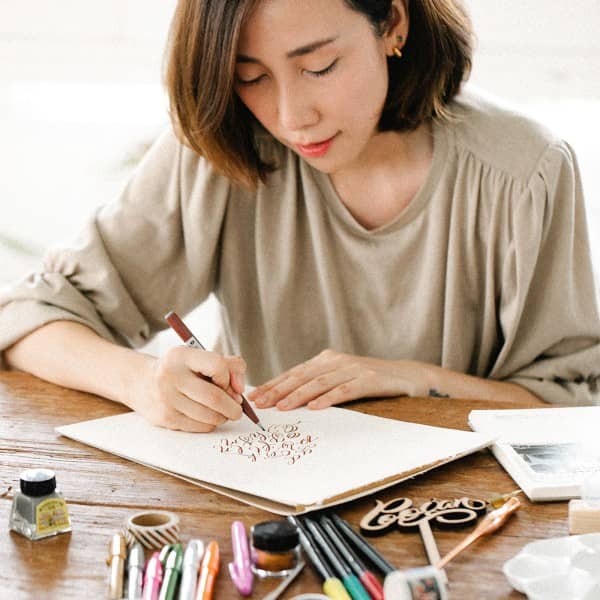 Eine Frau praktiziert auf einem Blatt Papier Kalligraphie