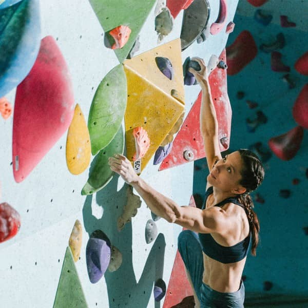 Eine Frau klettert beim Bouldern an einer Wand empor