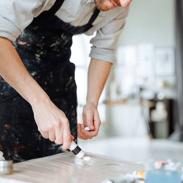 Mann trägt Farbe auf eine Leinwand auf