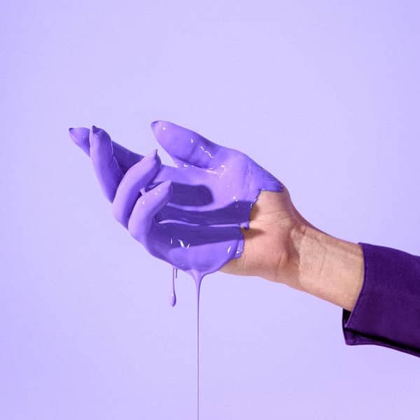 Hand in lila Farbe getaucht