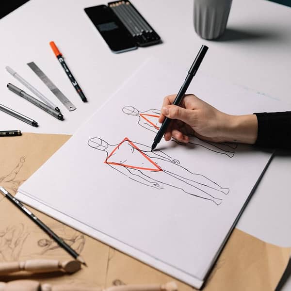 Menschliche Körperform auf Papier mit Stiften drumherum